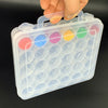 A hand holds a clear plastic storage container filled with colorful round bottles and label stickers.