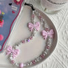 A delicate necklace featuring pink and clear acrylic pearl beads is displayed on a white plate.