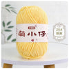 A ball of bright yellow chenille yarn with Chinese characters on the label, displayed on a white table.