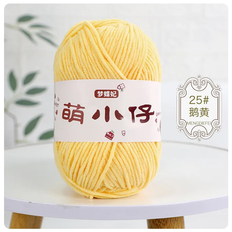 A ball of bright yellow chenille yarn with Chinese characters on the label, displayed on a white table.