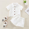 A white baby boy cotton linen summer shirt and shorts outfit set laid out on a light background.
