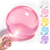 A hand holds a pink squishy stress ball next to several other colored clear squishies.