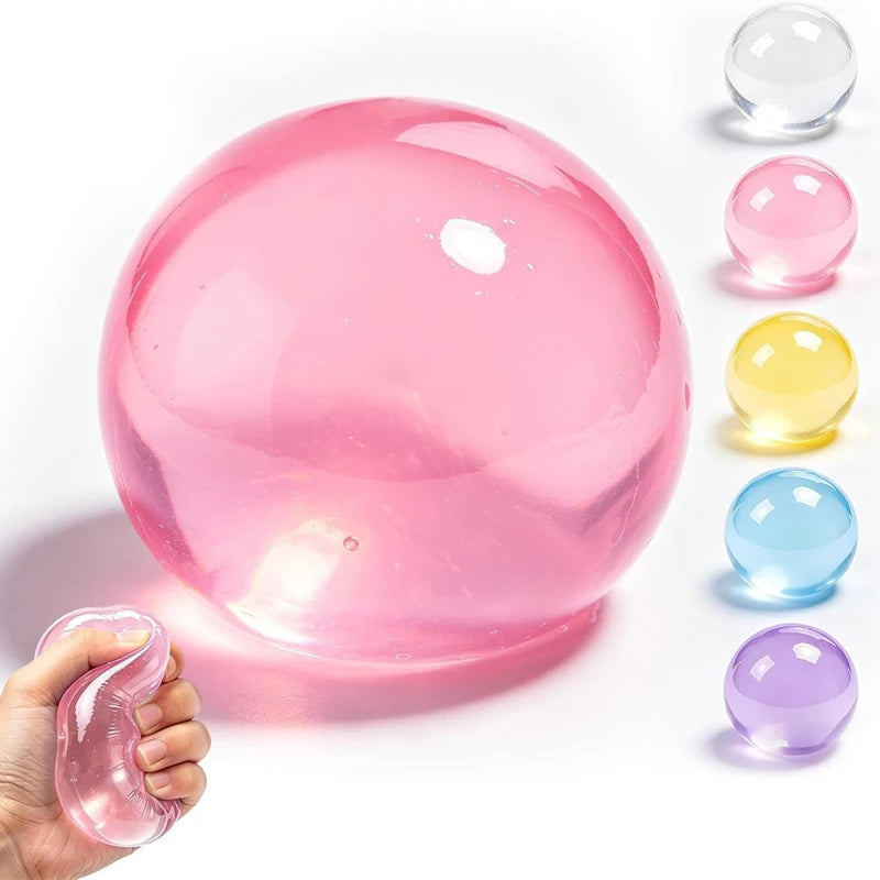 A hand holds a pink squishy stress ball next to several other colored clear squishies.