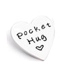 A white heart-shaped token with the words Pocket Hug written in black script.