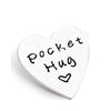 A white heart-shaped token with black handwritten text that reads Pocket Hug.
