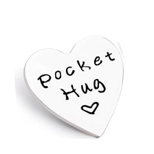 A white heart-shaped token with black handwritten text that reads Pocket Hug.