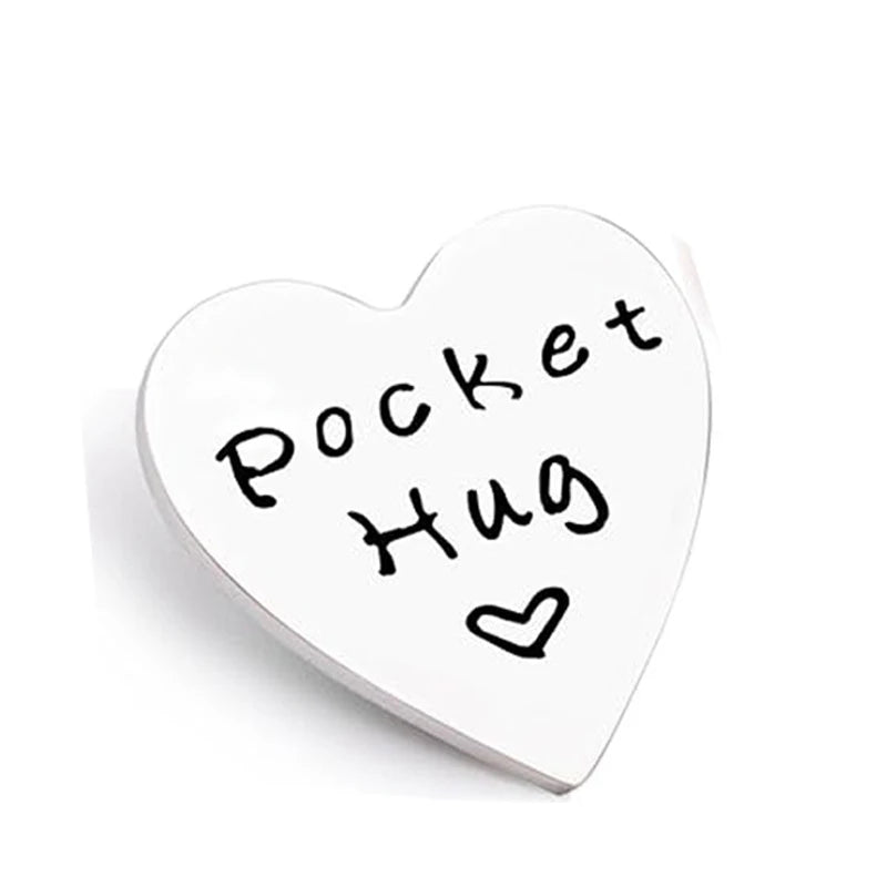 A white heart-shaped token with black handwritten text that reads Pocket Hug.