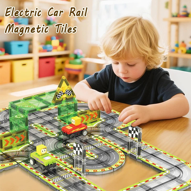 A young child plays with a green magnetic tiles electric car rail set on a wooden table.