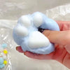 A hand holds a soft blue squishy toy shaped like a cat paw, with several white pads visible.