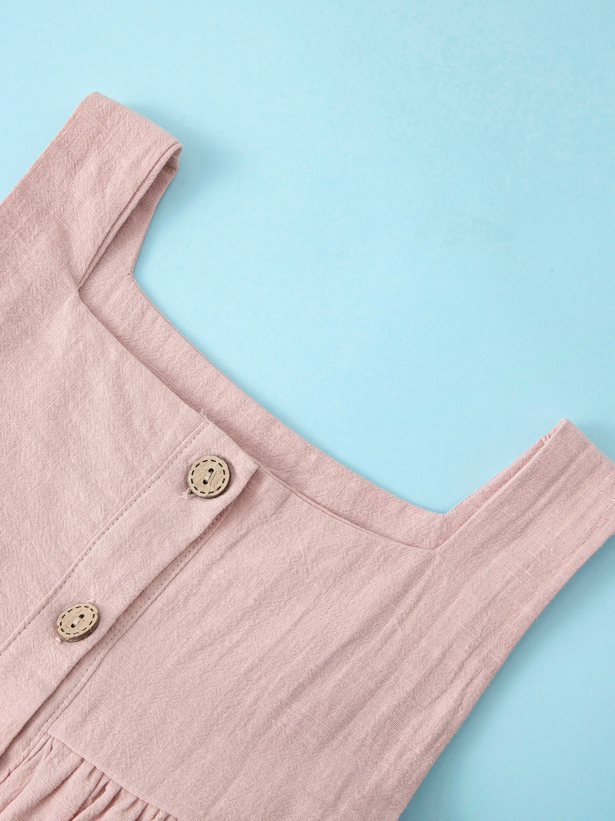 A light pink summer cotton linen jumper dress for a toddler girl, shown in a close-up view.