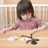 A young child is assembling a wooden stick puzzle toy set on a light wood table.