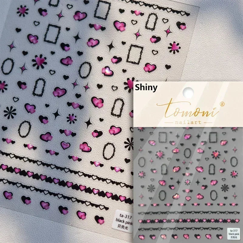 Sheet of shiny nail art stickers featuring pink and black hearts, stars, and geometric shapes