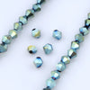 A close-up of blue and green faceted glass crystal beads arranged in a linear pattern.