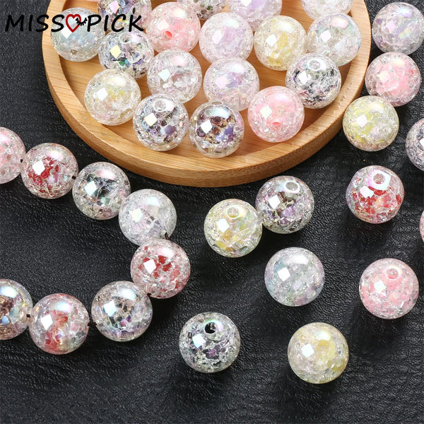 A collection of colorful glitter resin spacer beads in various shades and sizes arranged on a wooden tray and black surface.