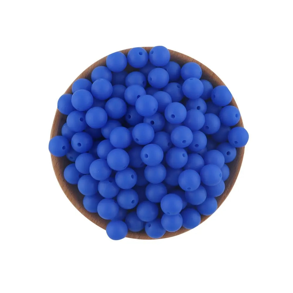 A pile of small, round blue silicone beads in a wooden bowl for jewelry making and crafts.