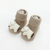 A pair of beige knitted cotton socks with a white cartoon sheep design for babies and toddlers.