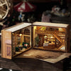 A wooden miniature dollhouse kit featuring detailed furniture and lighting elements displayed in an open box.
