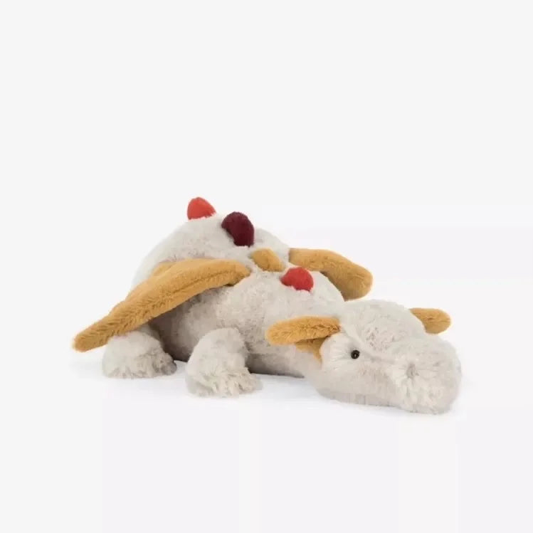 A fluffy white dragon plush pillow with tan ears and red accents.