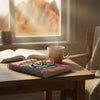 Une tasse de café marron, un journal ouvert et des lunettes sur une table en bois avec une vue montagne floue