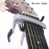 A silver aluminium alloy quick-release guitar capo clamped onto a guitar fretboard.
