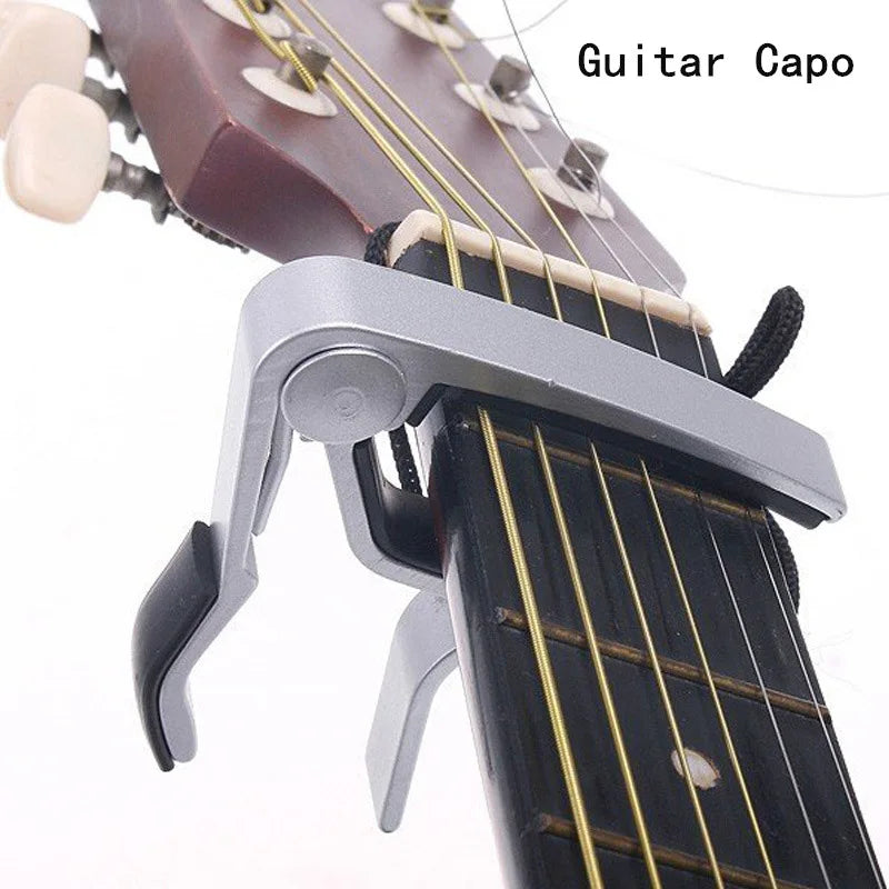 A silver aluminium alloy quick-release guitar capo clamped onto a guitar fretboard.