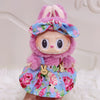 A plush doll wearing a pink and blue floral outfit with a bow and princess shoes.