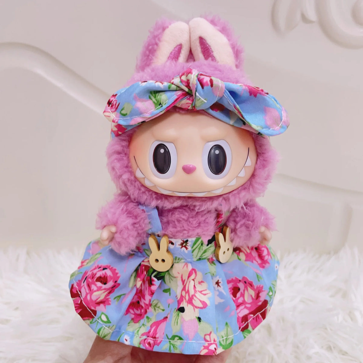 A plush doll wearing a pink and blue floral outfit with a bow and princess shoes.