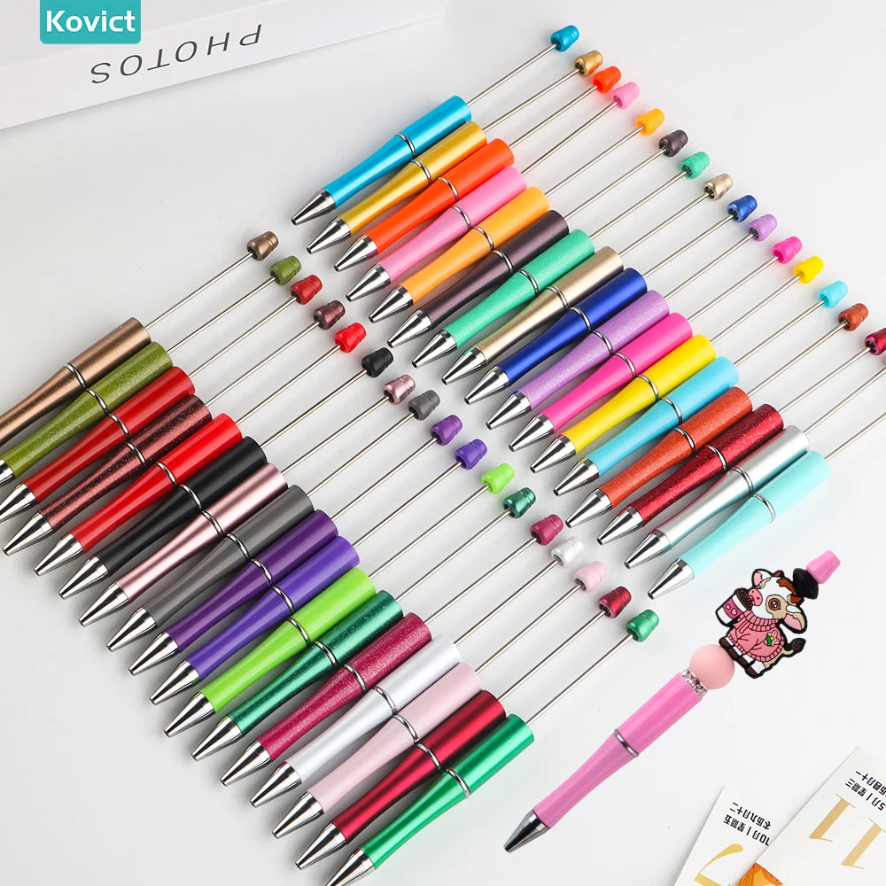 A collection of colorful beadable ballpoint pens with black ink arranged diagonally on a white surface.