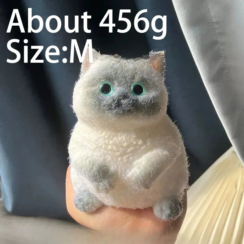 A white cat-shaped squishy stress relief toy with glowing blue eyes is held in a person's hand.