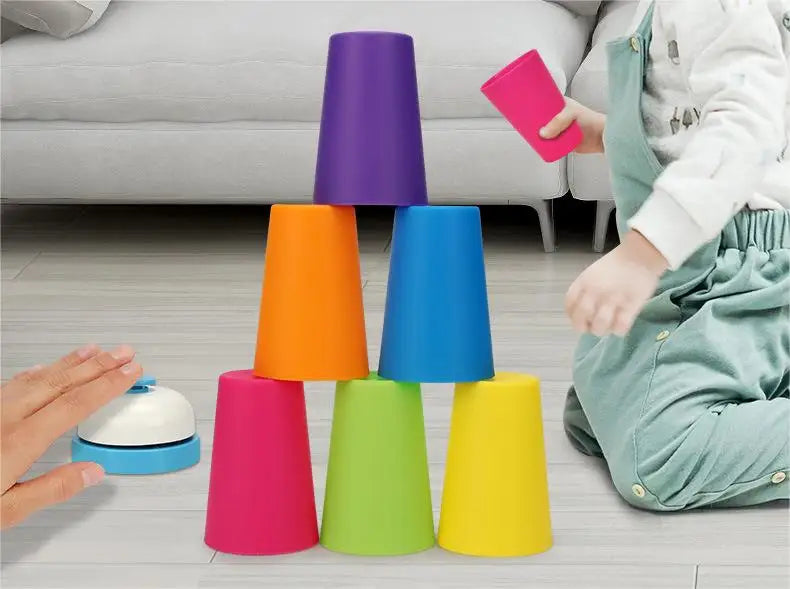 A set of colorful plastic stacking cups in various shades of purple, orange, blue, pink, and green are arranged on a floor.