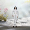 A plush doll resembling Michael Jackson with long black hair and white outfit standing in a snowy outdoor setting.