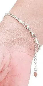 A close-up of a delicate silver chain necklace with magnetic clasps draped on a person's wrist.
