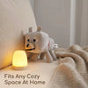 A light-up plush wolf toy resting on a white surface next to a knitted blanket.
