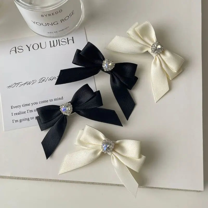 Black and white satin ribbon bows adorned with silver rhinestones displayed on a white background.