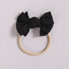 Black fabric bow headband with a light beige elastic band on a white background.