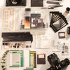 A collection of scrapbook stickers, paper, and crafting materials laid out on a white surface.