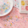 A spread of colorful gradient acrylic beads in various shades of pink, purple, and yellow scattered on a pink surface.