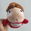 A close-up of a brown and red plush toy resembling a hippopotamus with large white eyes.