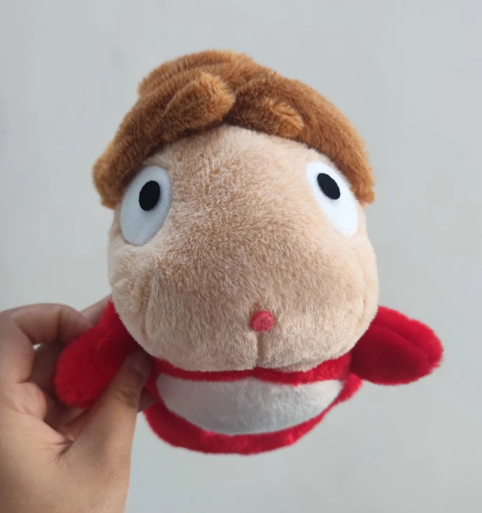A close-up of a brown and red plush toy resembling a hippopotamus with large white eyes.