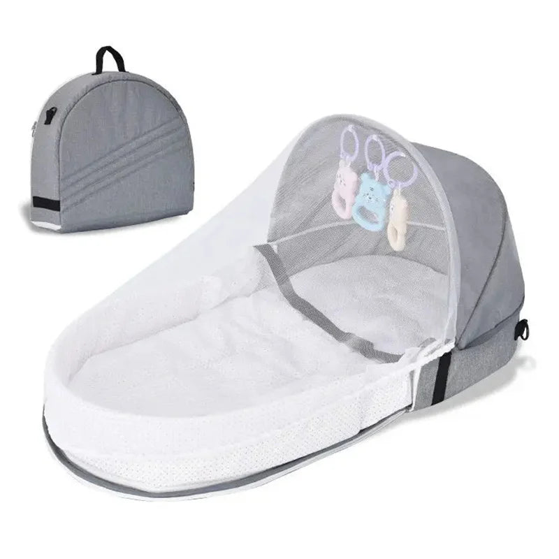A portable foldable baby bed with a mosquito net and mattress shown in gray.
