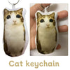 A soft, light brown and black cat plush keychain with a white tag.