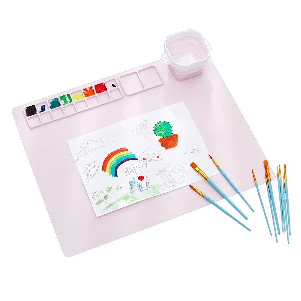 A pink painting mat set featuring a watercolor palette, various paint colors, and brushes for kids.