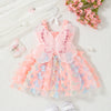 A pink butterfly-style dress for a baby girl with sheer fabric and floral accents, laid on a white surface.