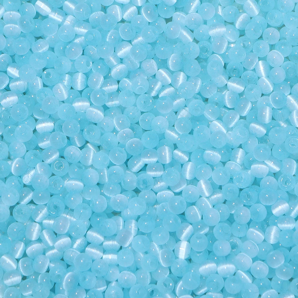 A close-up view of a mix of small, translucent light blue glass beads for jewelry making.