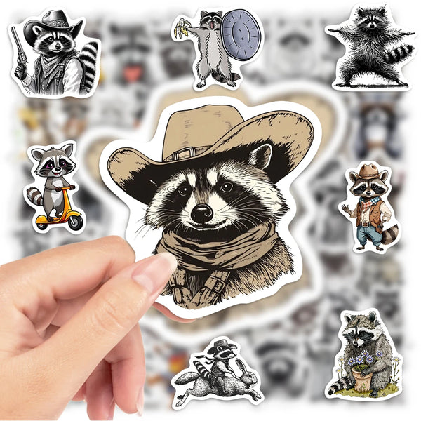 Eine Hand hält eine Sammlung lustiger Waschbär-Vinylaufkleber für Dekoration mit verschiedenen Waschbärenillustrationen.