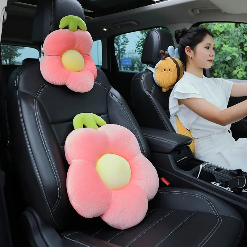 Pink and yellow plush lumbar support pillows with cute animal designs placed in the back seat of a car.