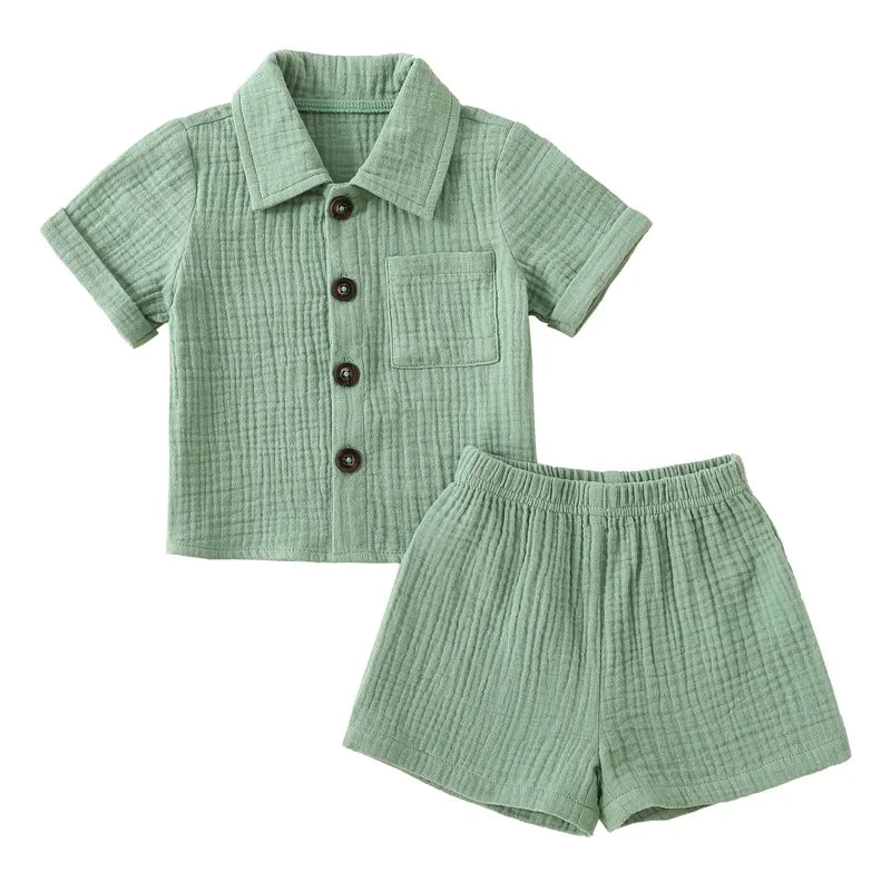 A baby boy cotton linen outfit set consisting of a short-sleeved shirt and matching shorts in a sage green color.