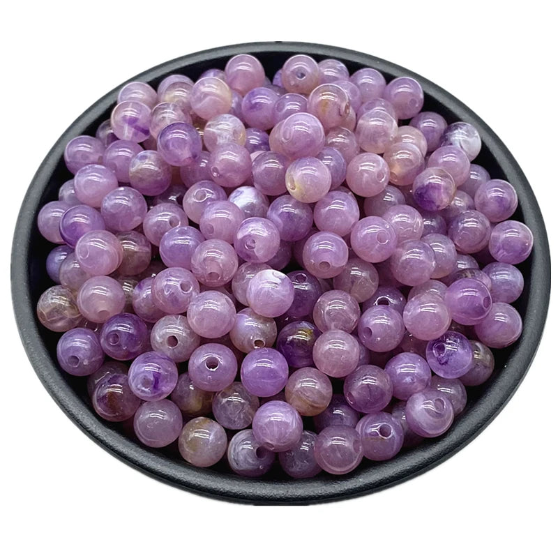 A pile of small, round purple acrylic beads for jewelry making.