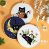 A set of embroidery kits featuring black cat designs on round fabric pieces with floral accents.