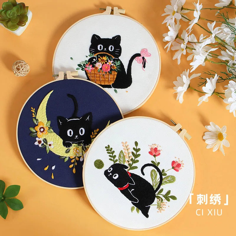 A set of embroidery kits featuring black cat designs on round fabric pieces with floral accents.